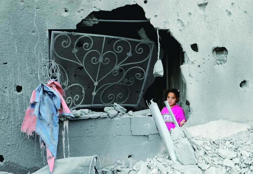 A child stands next to a hole in a damaged building as Palestinians inspect the site of an Israeli strike on a house, in Khan Yunis on Tuesday. — Reuters