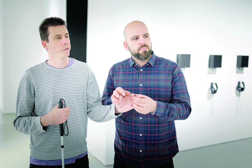 Olivier Mamini (L) and his image whisperer Pierre-Antoine Possa take part in a guided tour for visually impaired people in Geneva. - AFP