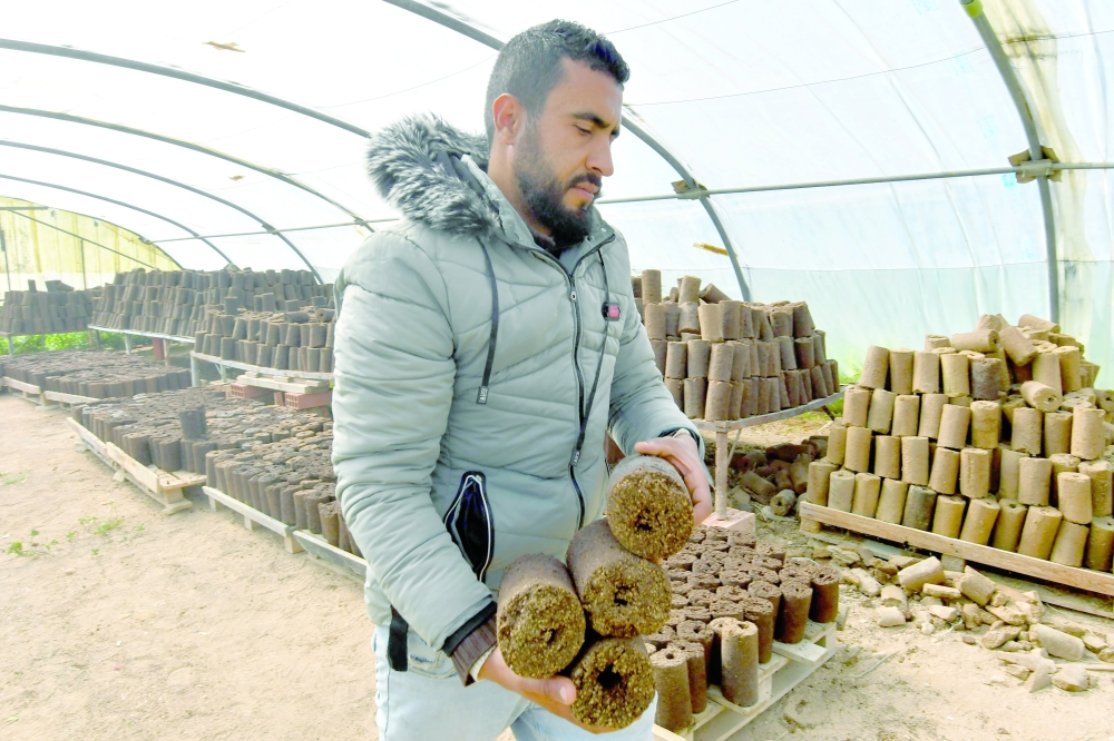 An employee carries rolls of olive pomace at the grounds of start-up Bioheat. - AFP