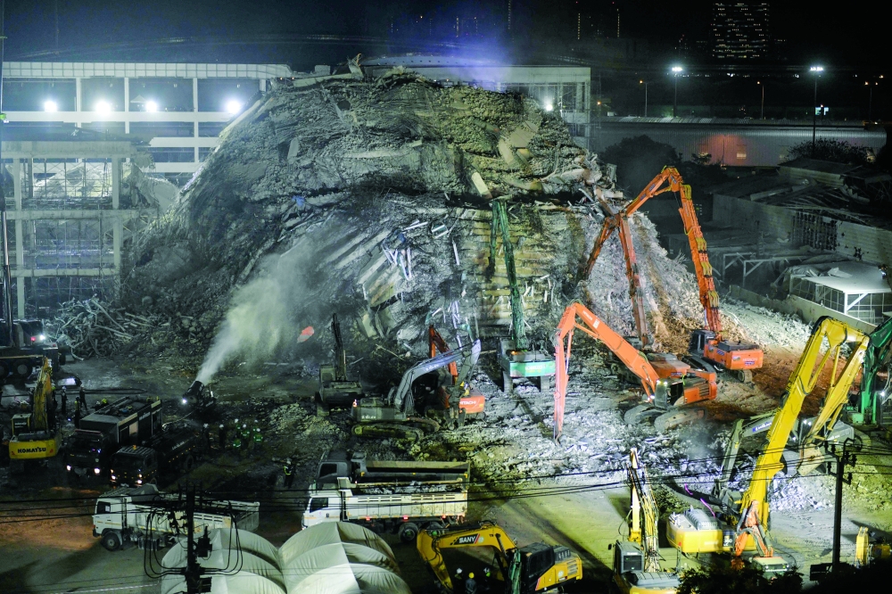 Heavy machinery is used to clear debris at the site of an under-construction building collapse in Bangkok. — AFP