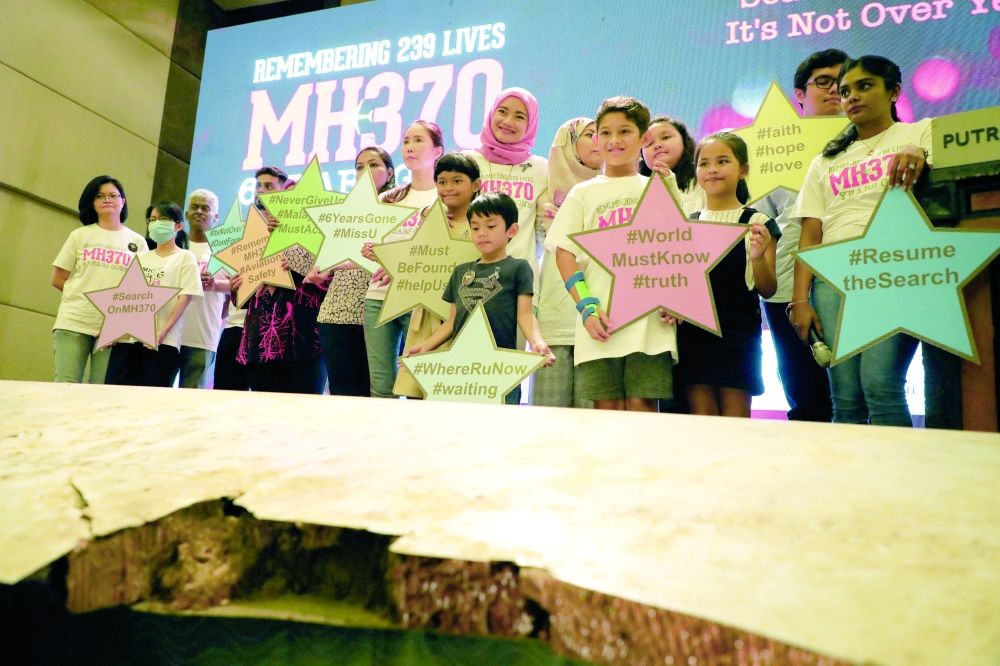 Family members of the victims pose with debris of the missing Malaysia Airlines flight MH370, Malaysia. — Reuters file photo