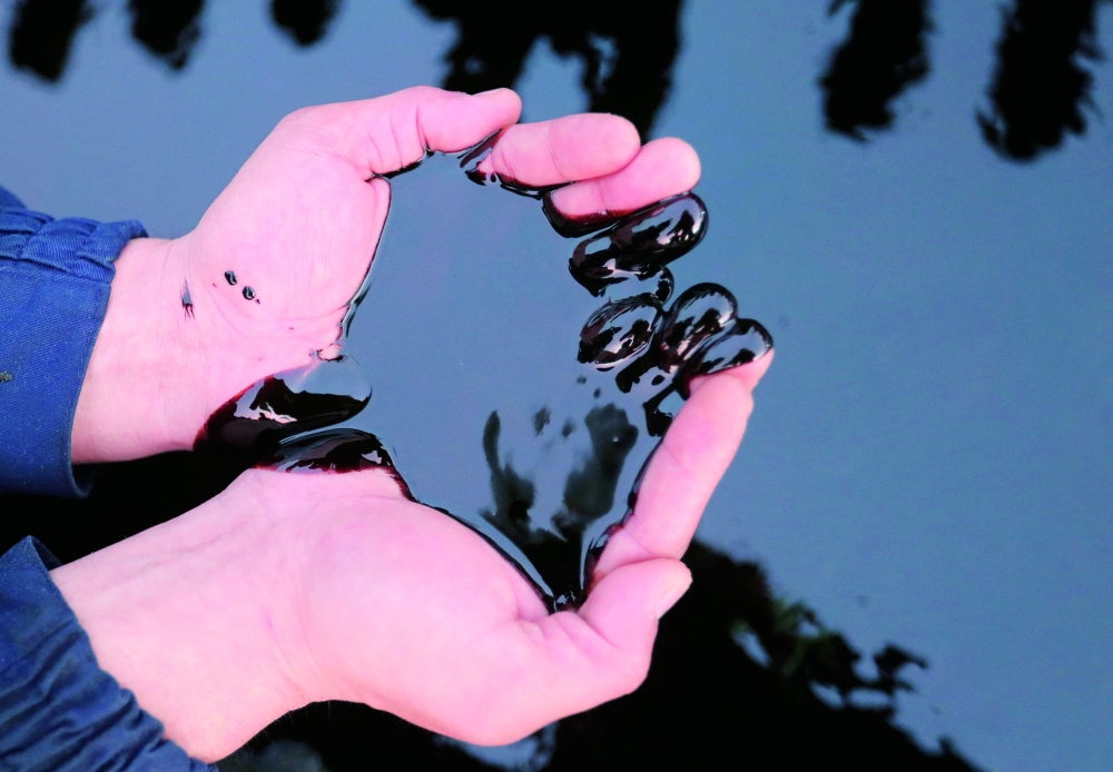 A man scoops up oil with his hands in this illustration taken at the Airankol oil field in the Atyrau Region, Kazakhstan. — Reuters