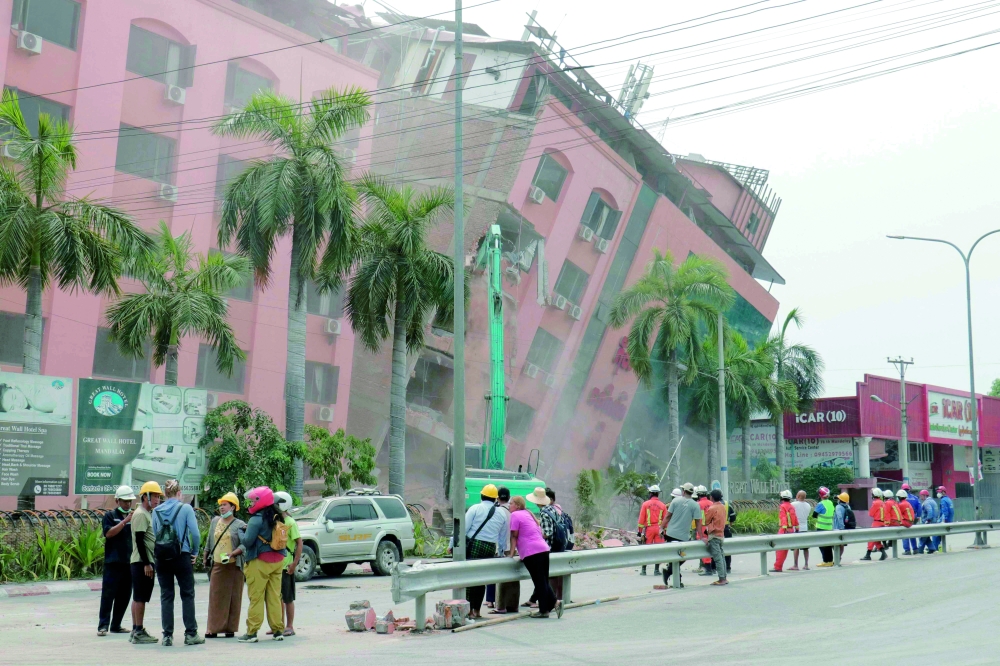 Rescue workers stand on the street next to a collapsed building in Mandalay, Myanmar. — AFP