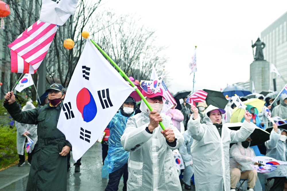 Supporters of Yoon wave US and South Korean flags as they attend a rally on a street in Seoul. — AFP