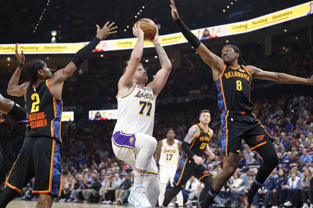 Los Angeles Lakers guard Luka Doncic (77) drives to the basket between Oklahoma City Thunder guard Shai Gilgeous-Alexander (2) and forward Jalen Williams (8) during the second quarter at Paycom Center. — Reuters