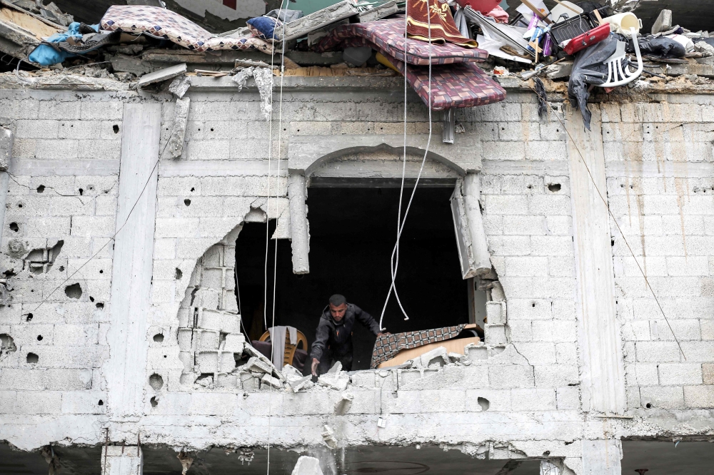 A man inspects the scene by a destroyed window after Israeli air strikes in Deir Al Balah. — AFP