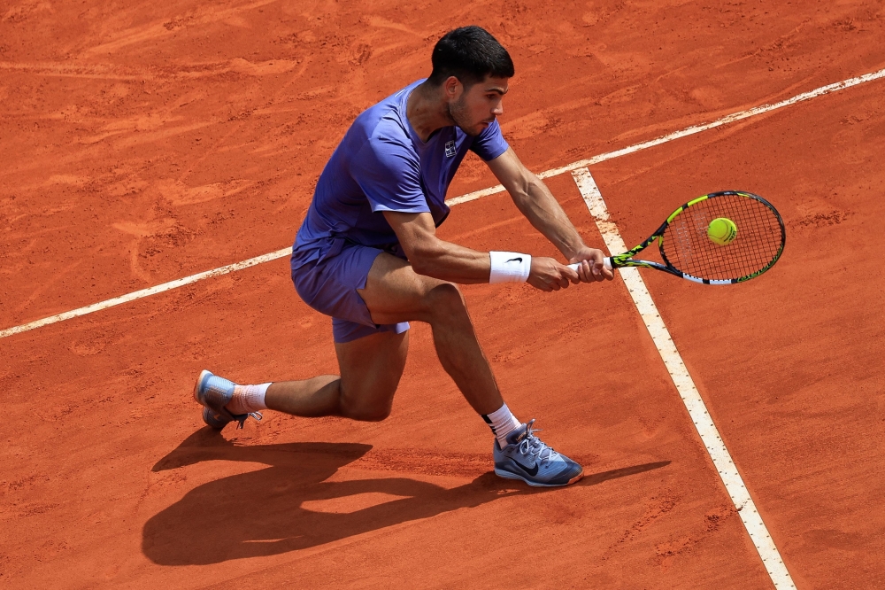 Spain's Carlos Alcaraz plays a backhand return to France's Arthur Fils during the Monte Carlo ATP Masters Series Tournament quarter-final tennis match at the Monte Carlo Country Club in Roquebrune-Cap-Martin on April 11, 2025.  (Photo by Valery HACHE / AFP)
