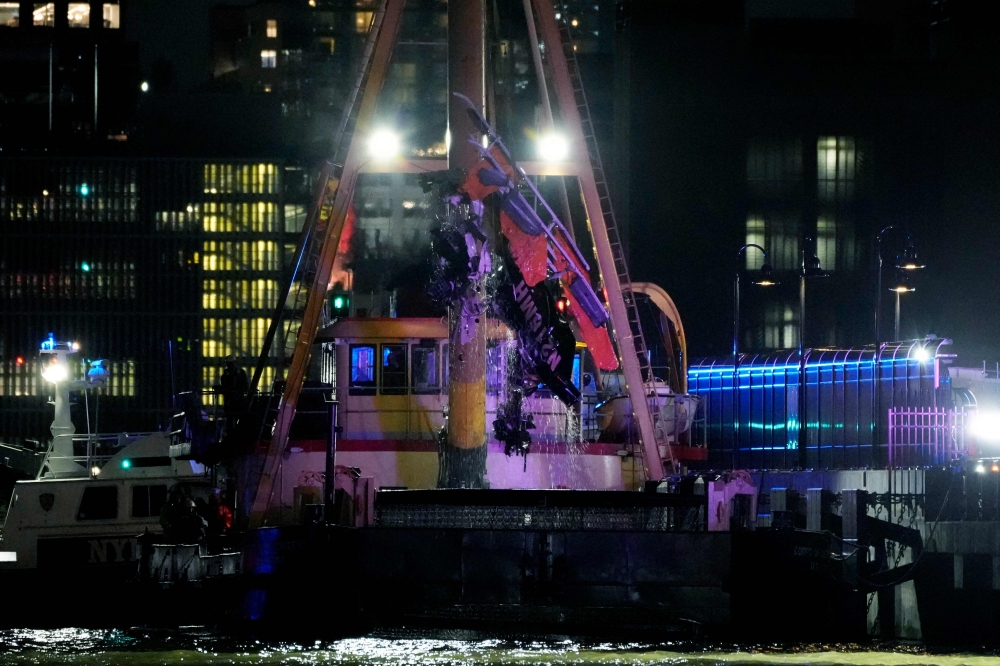 The wreckage of a helicopter is removed from the water after crashing into the Hudson River, in the Newport neighborhood of Jersey City, New Jersey. - AFP