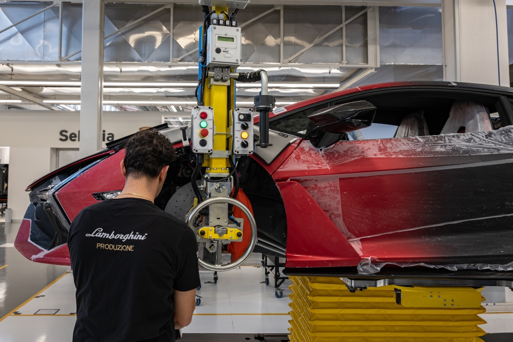 An employee works on the front wheel well of a car on the production line at the Lamborghini factory in Sant'Agata Bolognese, Italy, in February 2025. (Federico Borella/The New York Times)