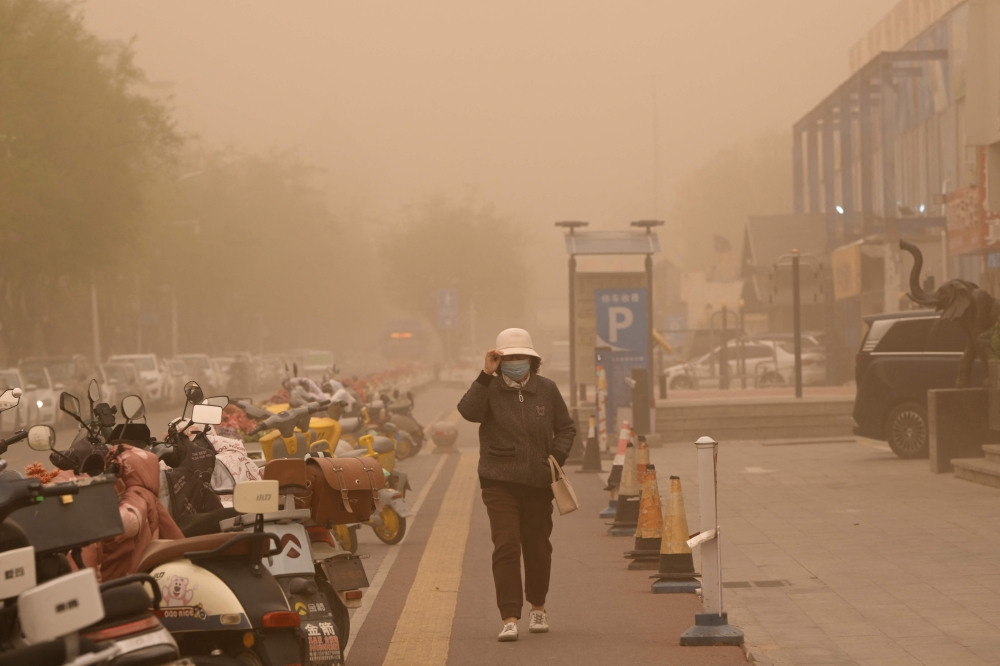 A woman walks during a sandstorm in Yinchuan, in northern China. — AFP