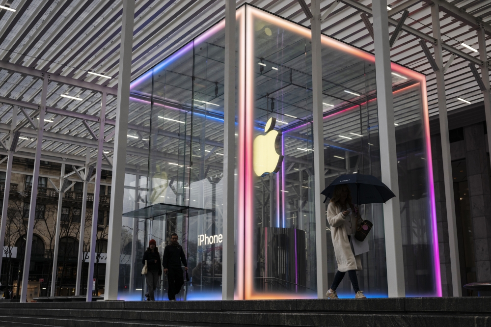 A person walks past a glowing sign of a Chanel store in New York on April 7, 2025. (Karsten Moran/The New York Times)