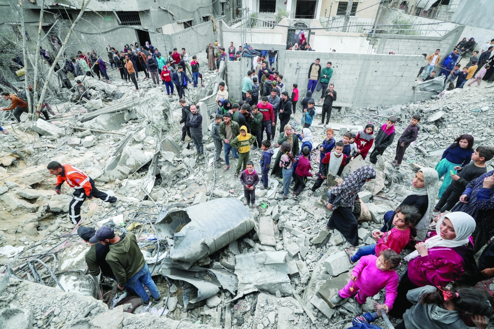 Palestinians gather at the site of an Israeli strike to remove casualties from under the rubble, in Jabalia. — Reuters