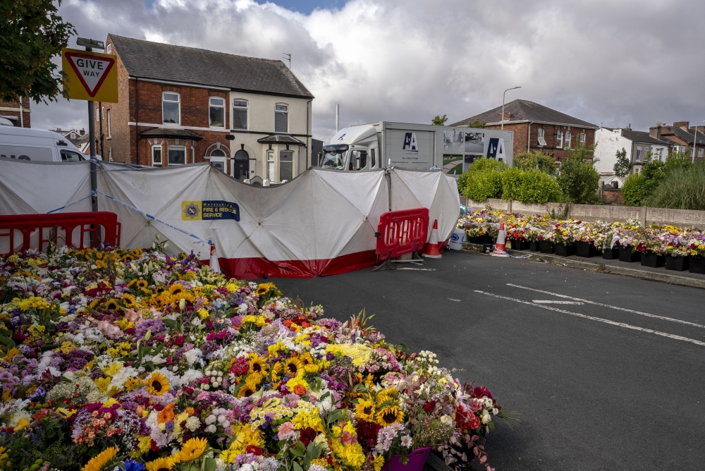Both sidewalks overflow with flowers in memory of three girls killed at dance class, near the school in Southport, England, Aug. 9, 2024. (Andrew Testa/The New York Times)