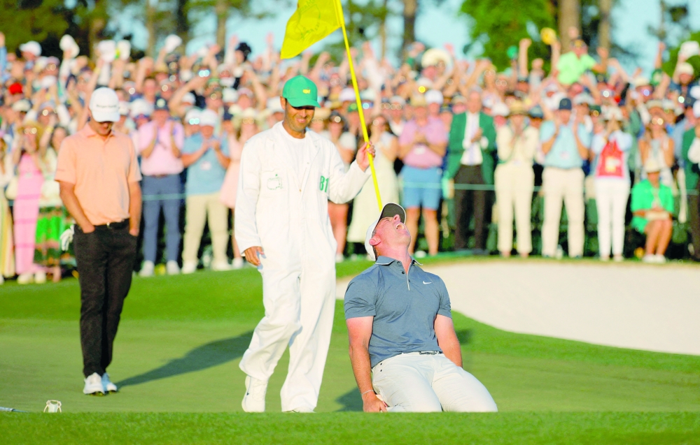 Northern Ireland's Rory McIlroy celebrates on the 18th green of the 1st play-off hole after winning The Masters and completing a career grand slam with his caddie Harry Diamond holding the pin and England's Justin Rose looking dejected REUTERS/Mike Blake     TPX IMAGES OF THE DAY
