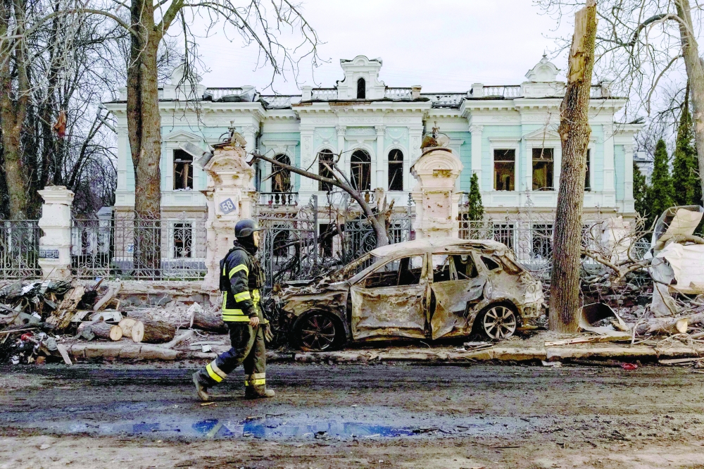 A Ukrainian rescuer walks by a burned car in front of a damaged building at the site of a missile attack in Sumy. — AFP