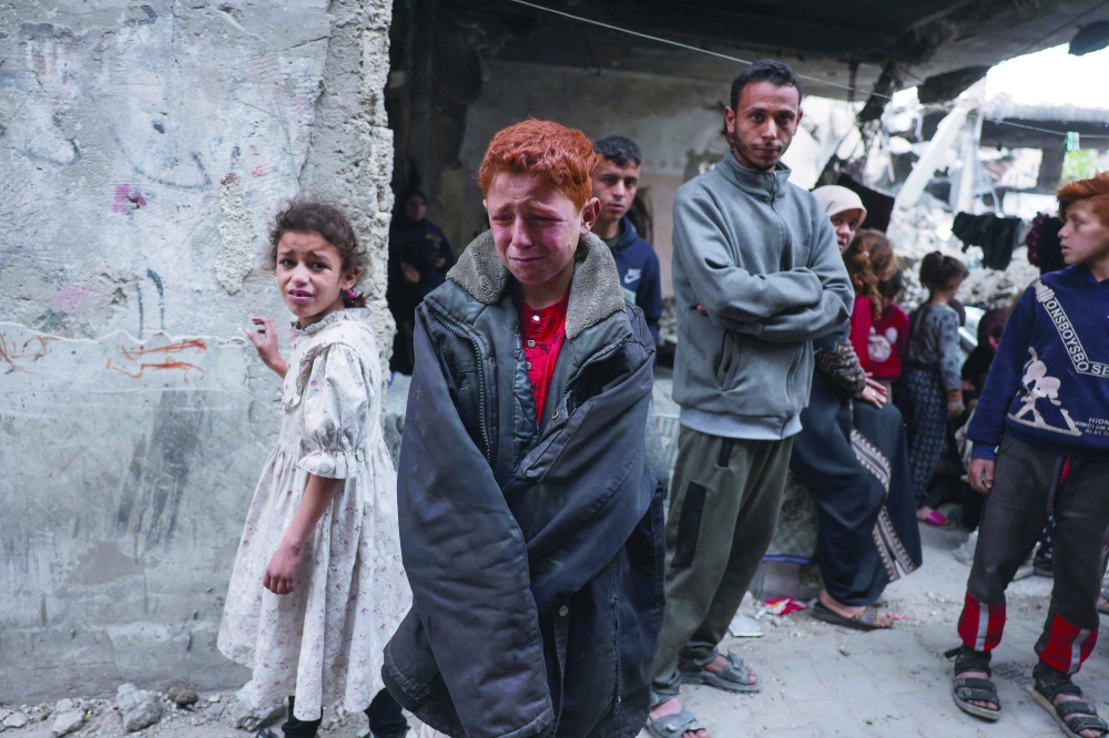 Palestinian children cry as rescuers search for casualties in the rubble, in Jabalia. — AFP