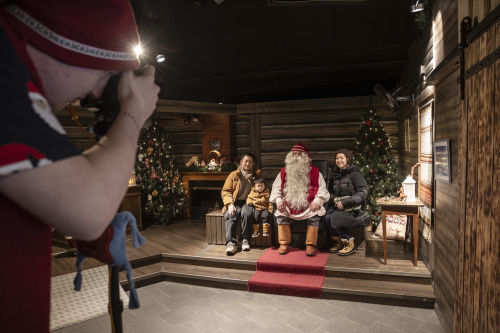 Tourists have their picture taken with one of the Santas at Santa Claus Village outside Rovaniemi, Finland, Feb. 23, 2025. (Jim Huylebroek/The New York Times)