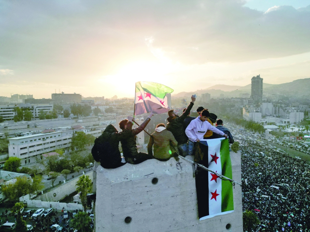 A drone view shows people waving Syrian flags, in Damascus. — Reuters