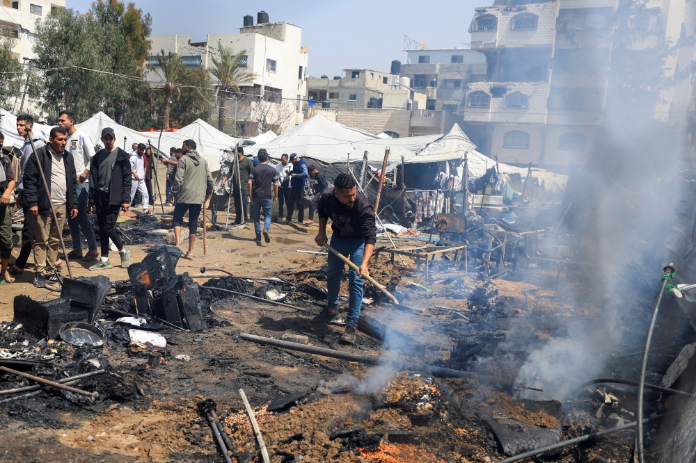 Palestinians inspect the site of an Israeli strike on a tent camp sheltering displaced people in Gaza City. — Reuters