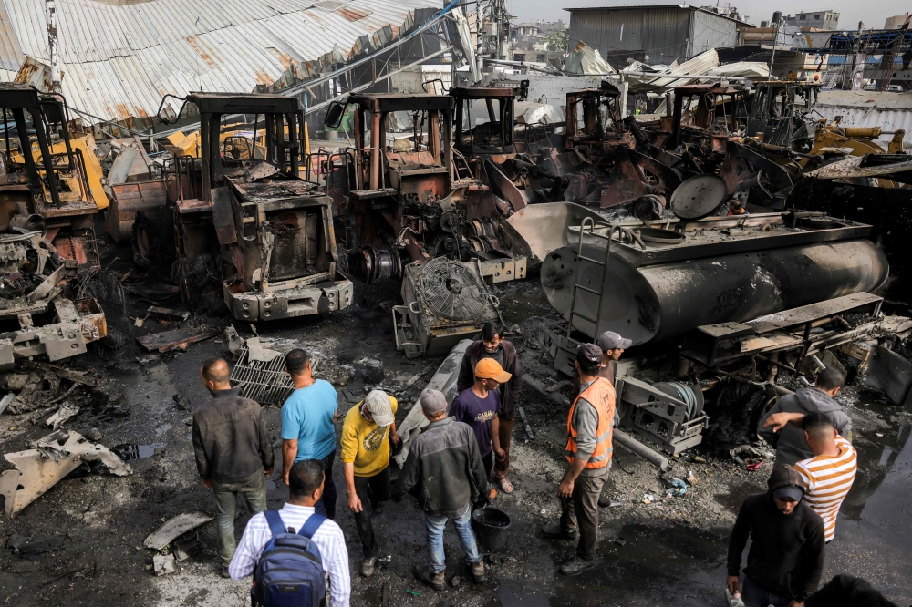Men inspect destroyed bulldozers