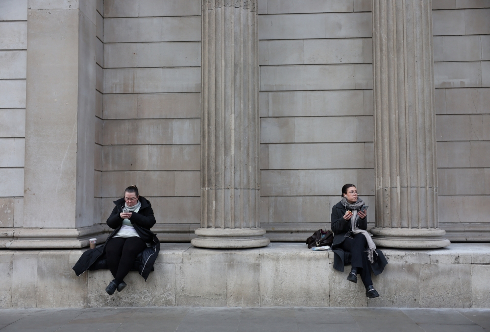 Office workers take a lunch break outside the Bank of England, in London, Britain. — Reuters