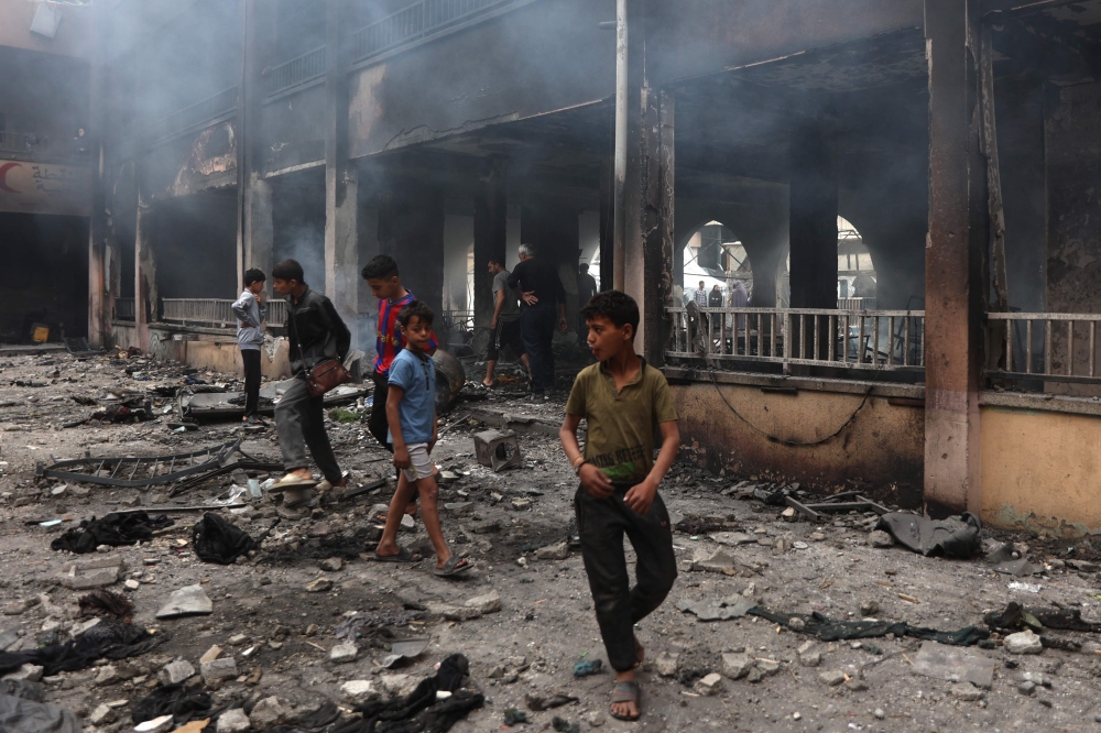 Palestinians inspect the damage after an Israeli strike on a school housing displaced, in Gaza. — AFP