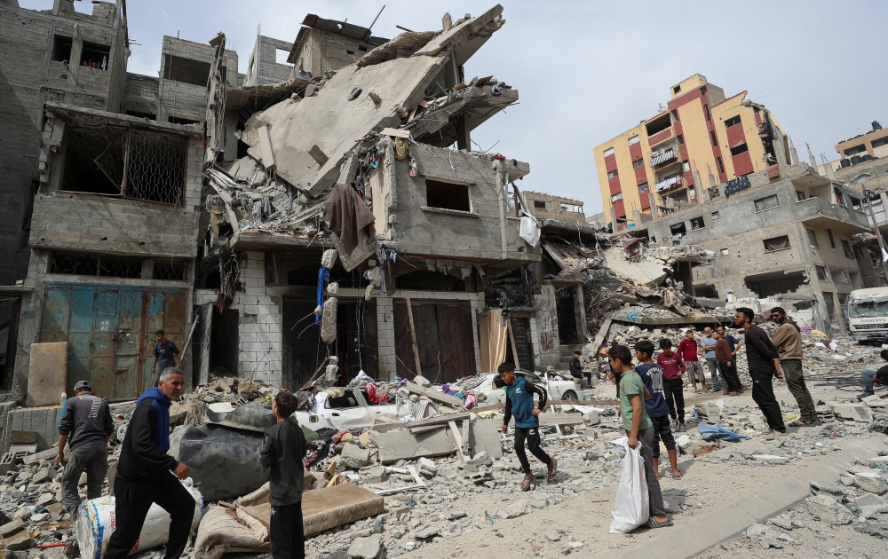 Palestinians gather at the site of an Israeli strike on a house in Gaza City. - Reuters

