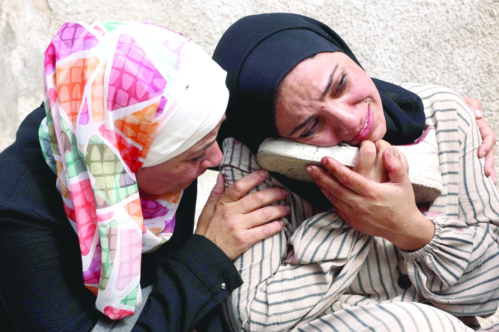 A Palestinian woman mourns as she holds the blood-stained shoe of a loved one, who was killed during an Israeli strike earlier on Al Jalaa street in the central Gaza Strip on Monday. — AFP