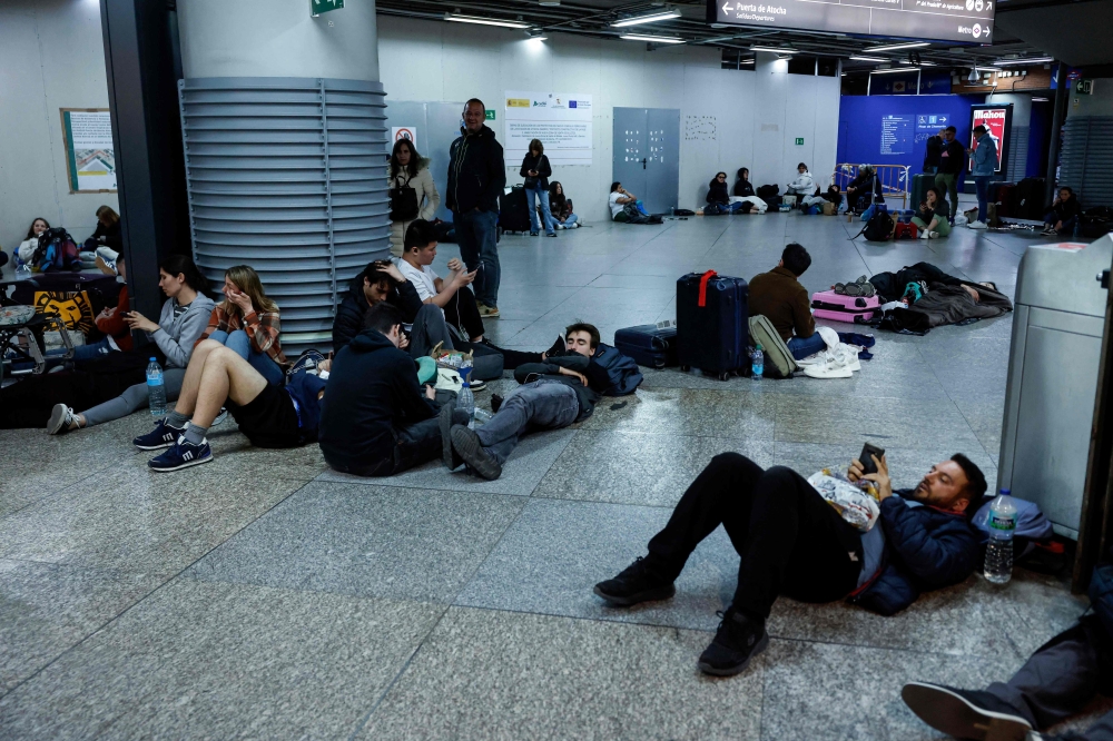 Travelers lie on the floor as they prepare to spend the night at the train station