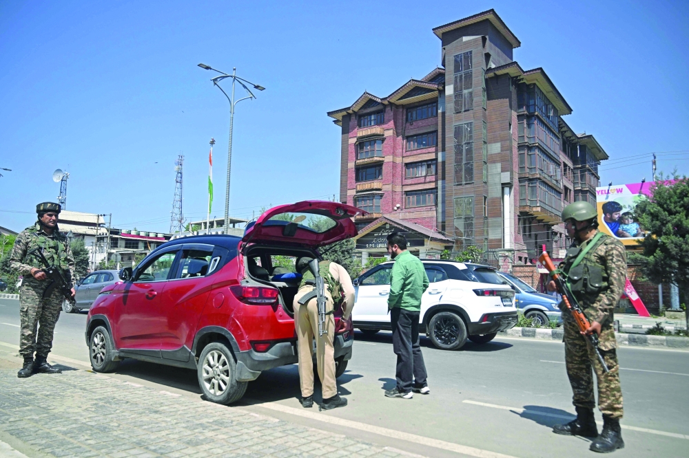 Indian paramilitary troopers stand guard as a policeman searches a car, in Srinagar. — AFP