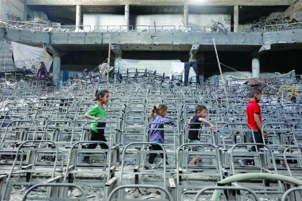Displaced Palestinian children play at a damaged lecture hall at the Islamic University campus in Gaza City. — AFP