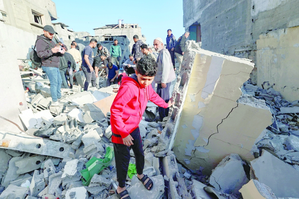 A child looks on as people look for survivors in the rubble of a building hit in an Israeli strike in the Bureij camp for Palestinian refugees in the central Gaza Strip on Friday. — AFP