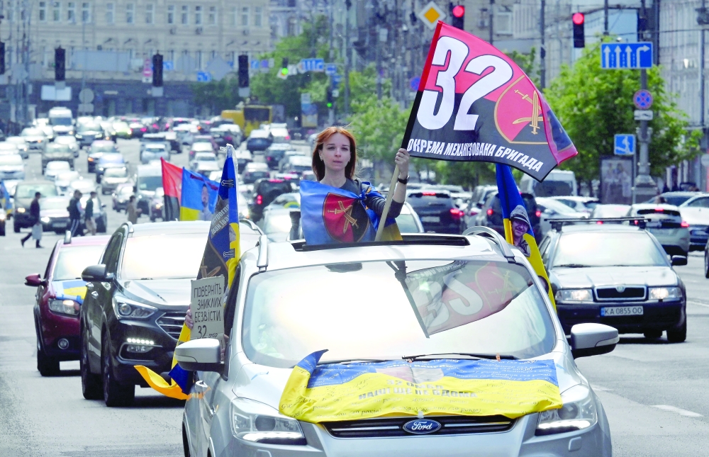 A young woman holds a flag of the 32nd Ukrainian Mechanized Brigade during a car rally calling to speed up exchanges of prisoners and the search of missing servicemen, in Kyiv. — AFP