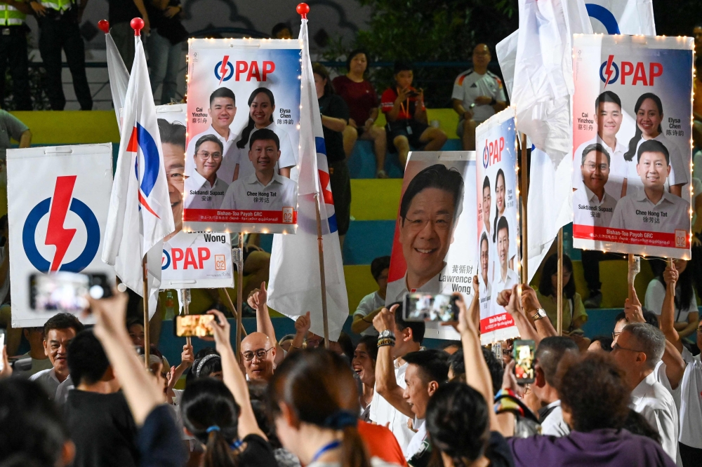 Supporters of the ruling People's Action Party (PAP) cheer on the party, in Singapore. — AFP