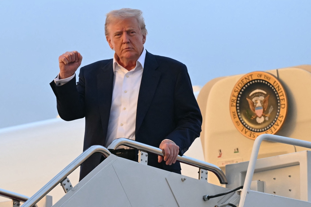 US President Donald Trump disembarks from Air Force One upon arrival at Joint Base Andrews in Maryland. - AFP


