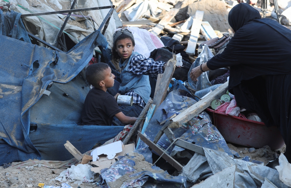 Palestinians inspect the site of an Israeli strike on an UNRWA school 