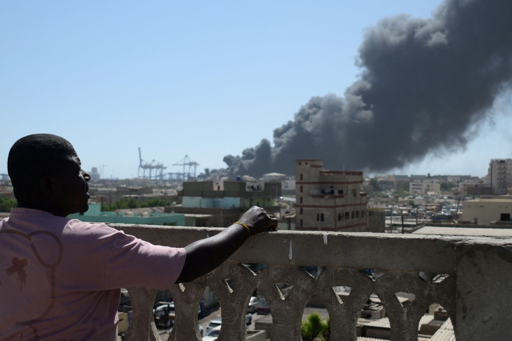 A man watches as smoke billows after a drone strike on the port of Port Sudan. — AFP