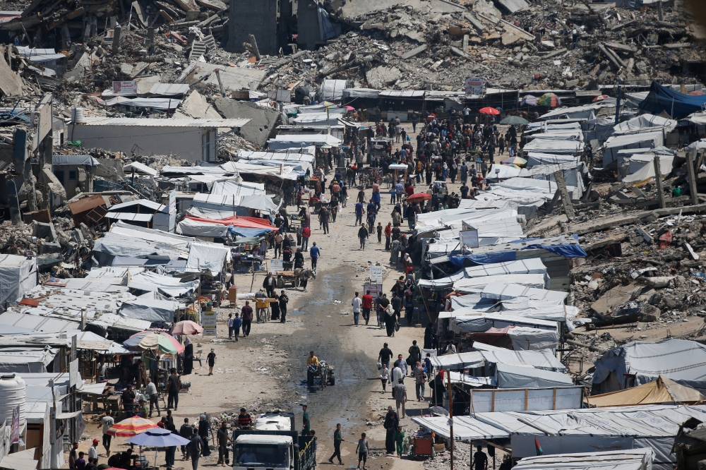 Palestinians shop at a market near the rubble of houses in Jabalia refugee camp, in the northern Gaza Strip, May 8, 2025. REUTERS/Mahmoud Issa
