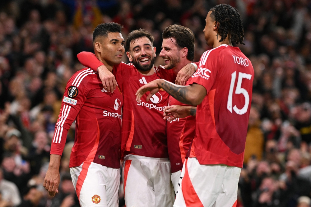 Manchester United's Brazilian midfielder #18 Casemiro (L) celebrates with teammates after scoring Manchester United's second goal during the UEFA Europa League semi final second leg football match between Manchester United and Athletic Club Bilbao at Old Trafford stadium in Manchester, north west England, on May 8, 2025. (Photo by Oli SCARFF / AFP)


