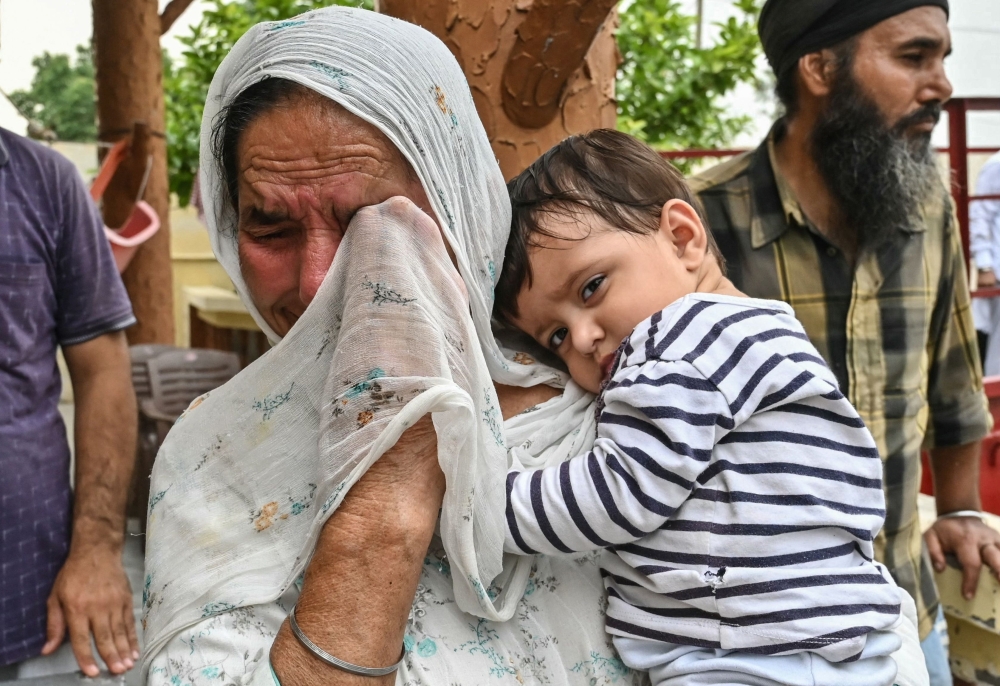 A woman carrying a child breaks down as they evacuate following a surge in border tensions, in Havelian village near the India-Pakistan border post, about 45kms from Amritsar. - AFP