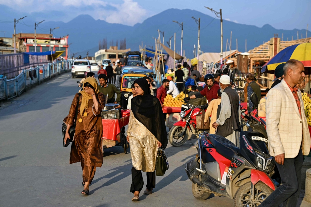 Locals walk past vendors along a roadside in Srinagar on Saturday. Pakistan and India agreed to a full and immediate ceasefire after days of jet fighter, missile, drone and artillery attacks. AFP