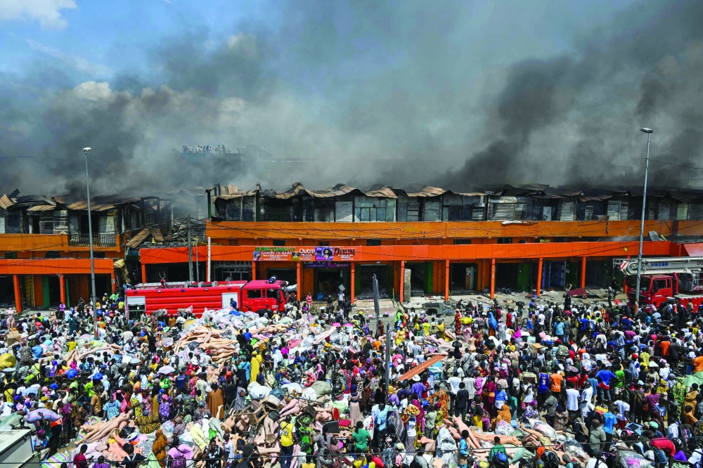 A crowd watches as smoke billows from stalls at the Adjame market in Abidjan.