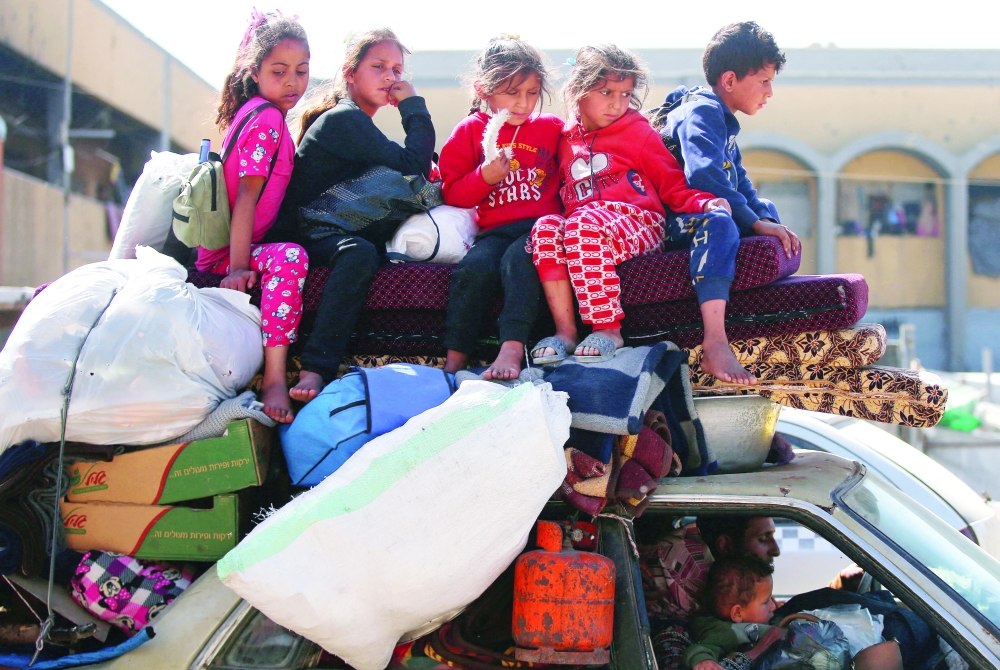 Palestinians make their way with belongings as they fled their homes, after Israeli air strikes, in the northern Gaza Strip on Saturday. — Reuters