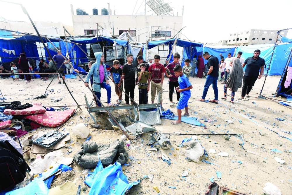 Palestinians inspect the site of an Israeli air strike on a tent sheltering displaced people, in Deir Al Balah. — Reuters