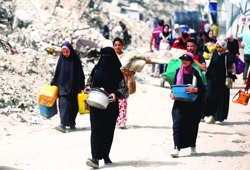 Palestinians make their way with belongings as they flee their homes, after Israeli air strikes, in the northern Gaza Strip on Saturday. — Reuters