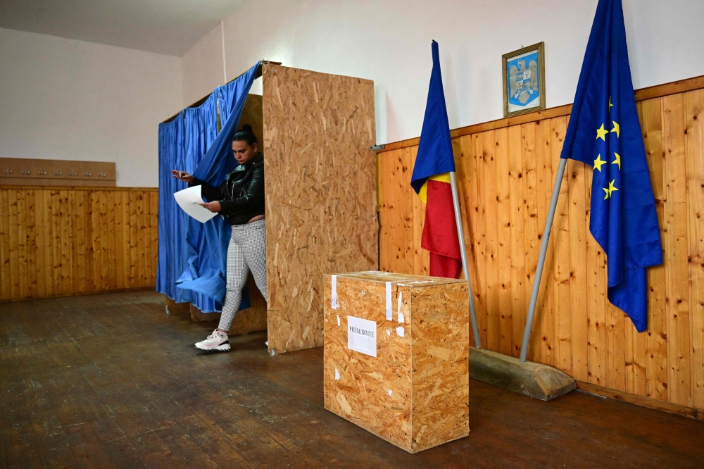 A voter leaves a cabin to cast her ballot at a polling station in Persani, central Romania. — AFP