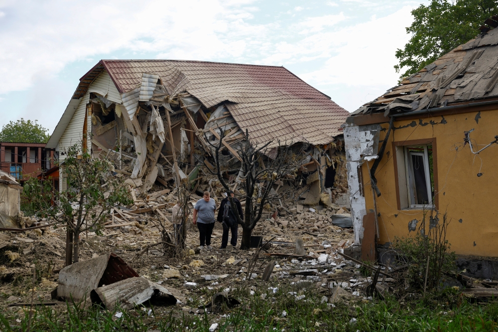 Resident Vadym Tsybenko, 22-year-old, stands next to his house and a house of his neighbours, heavily damaged by a Russian drone strike, amid Russia's attack on Ukraine, outside of Kyiv, Ukraine May 18, 2025. REUTERS/Valentyn Ogirenko