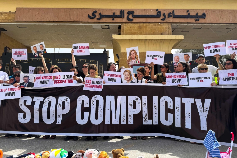 Italian, European parliament members hold placards during a protest in front of the Egyptian side of the Rafah border crossing. — AFP