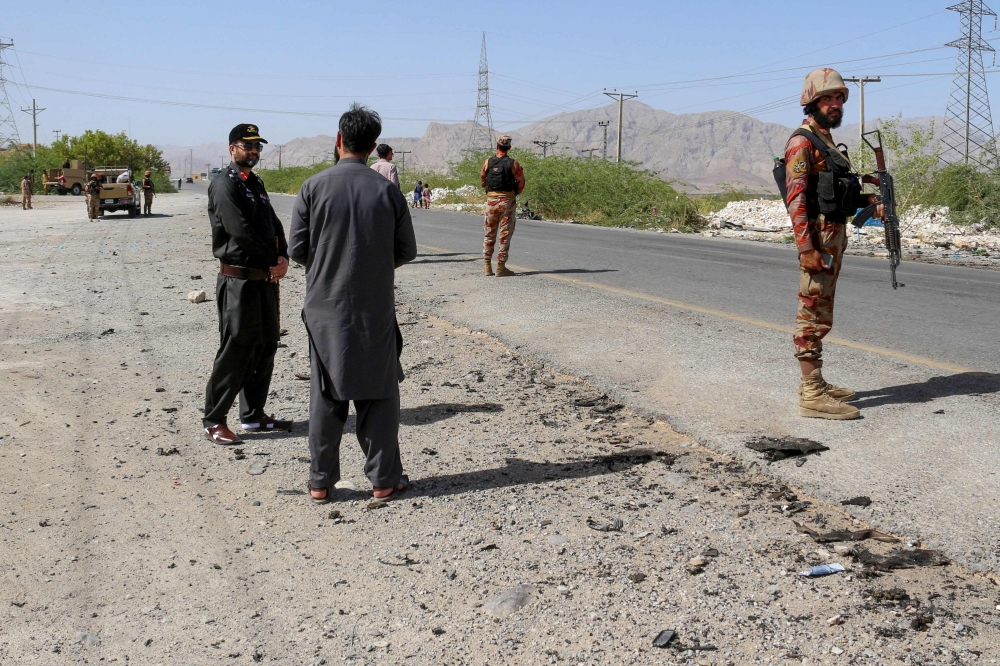 Security personnel stand guard at the site of a school bus bombing in Khuzdar district of Balochistan. — AFP