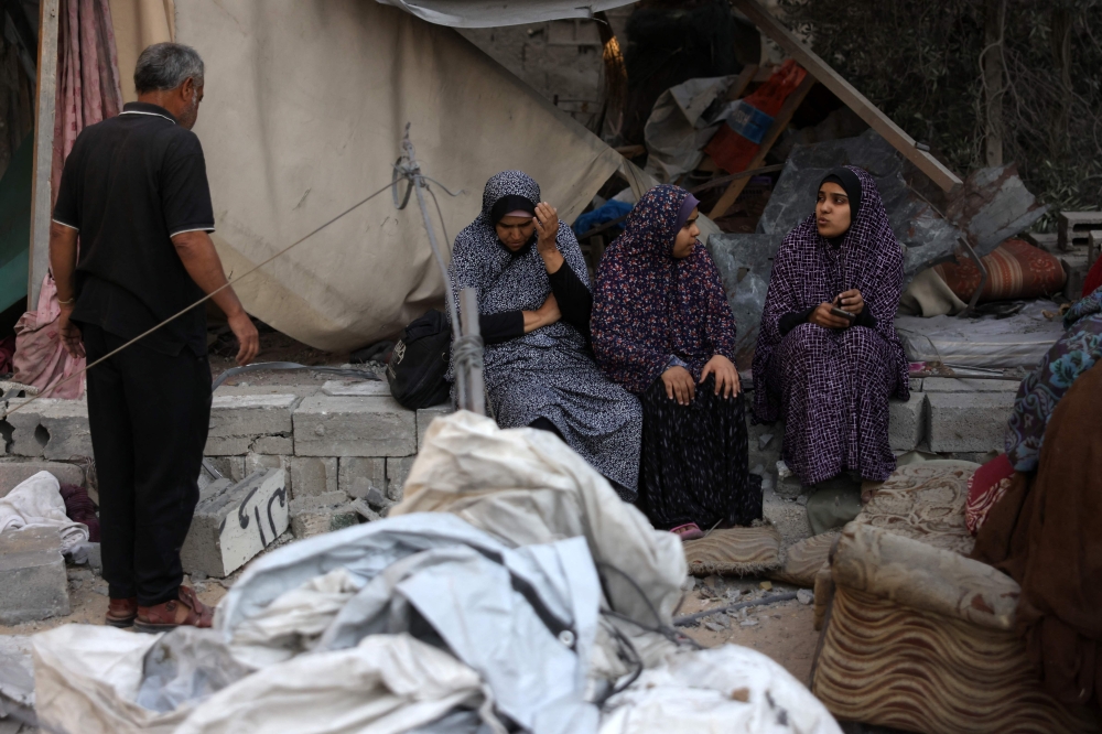 Displaced Palestinians sit amid the destruction in front of their damaged tent, following Israeli strikes in Jabalia. — AFP 
